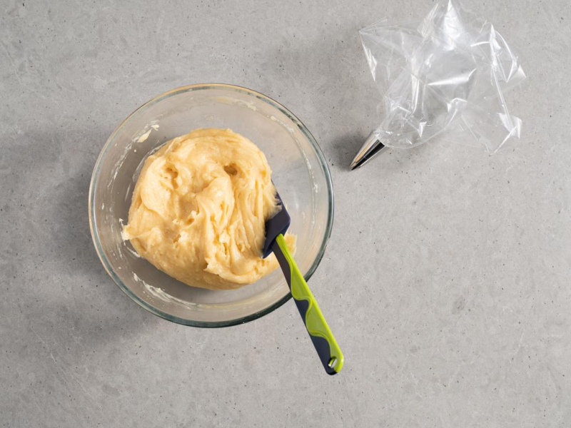 ciasto parzone na ptysie w szklanej misce, obok rękaw cukierniczy z ozdobną tylką