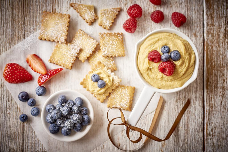 hummus waniliowy w miseczce z truskawkami i borówkami, dookoła kruche herbatniki
