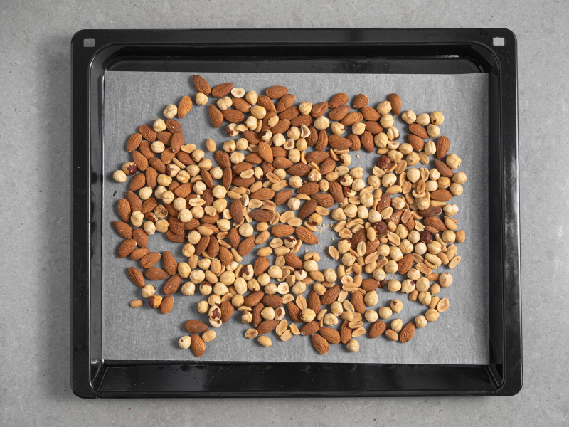 mieszanka orzechów laskowych, ziemnych i migdałów na blasze do pieczenia wyłożonej papierem do pieczenia