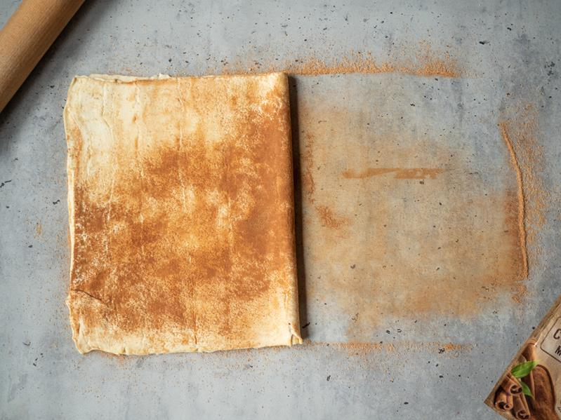 złożony arkusz ciasta francuskiego przesypany cukrem z cynamonem