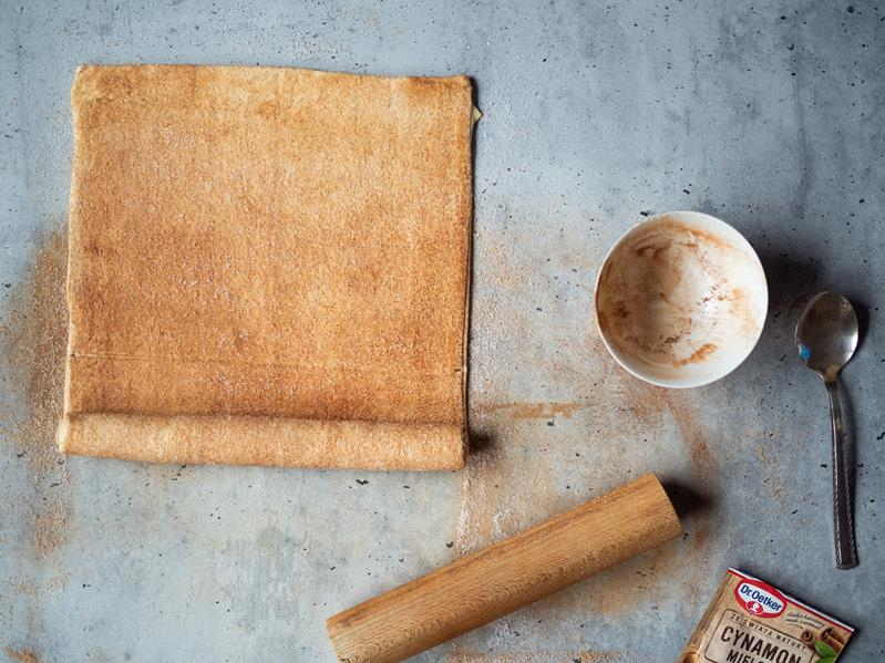 na stole drewniany wałek, miseczka po cynamonie Dr. Oetkera obok ciasto francuskie na palmiery