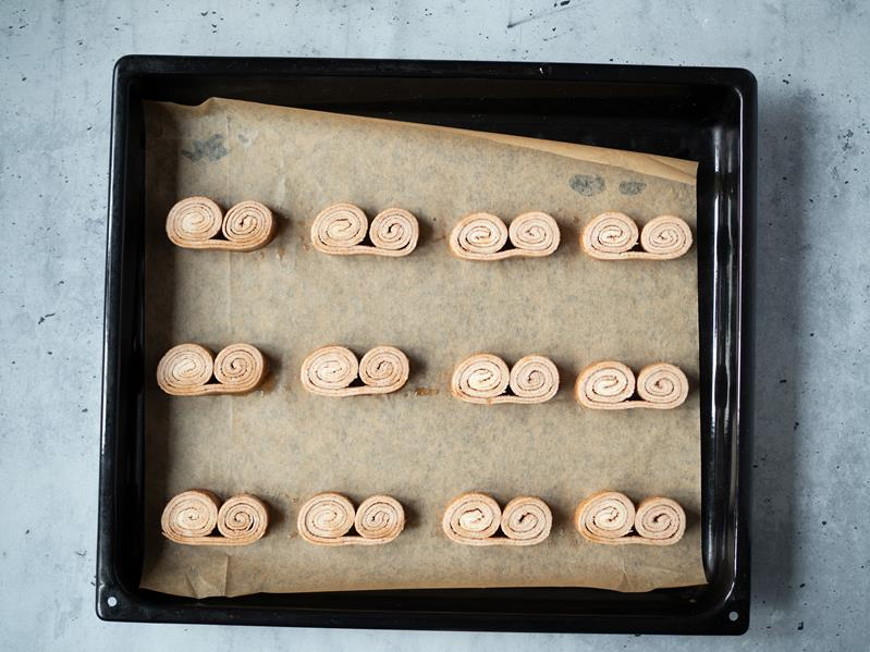 palmiery z cukrem i cynamonem ułożone na papierze do pieczenia na blasze przed upieczeniem