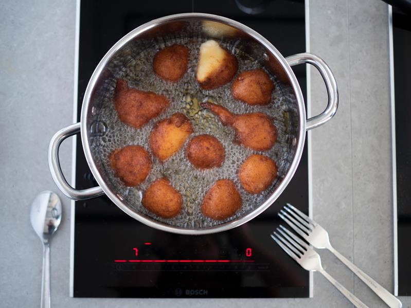 na palniku kuchenki garnek ze smażącymi się w oleju pączkami
