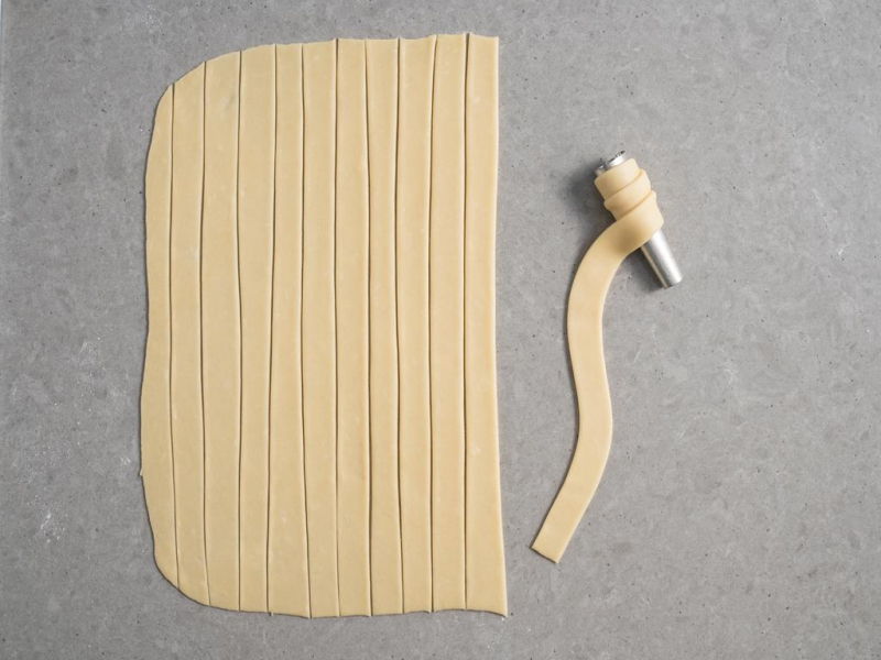 nawijanie pasków ciasta na metalowe rurki