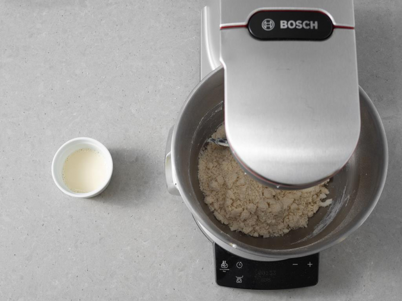 w misie miksera bosch wegańskie ciasto kruche, obok miseczka z napojem sojowym