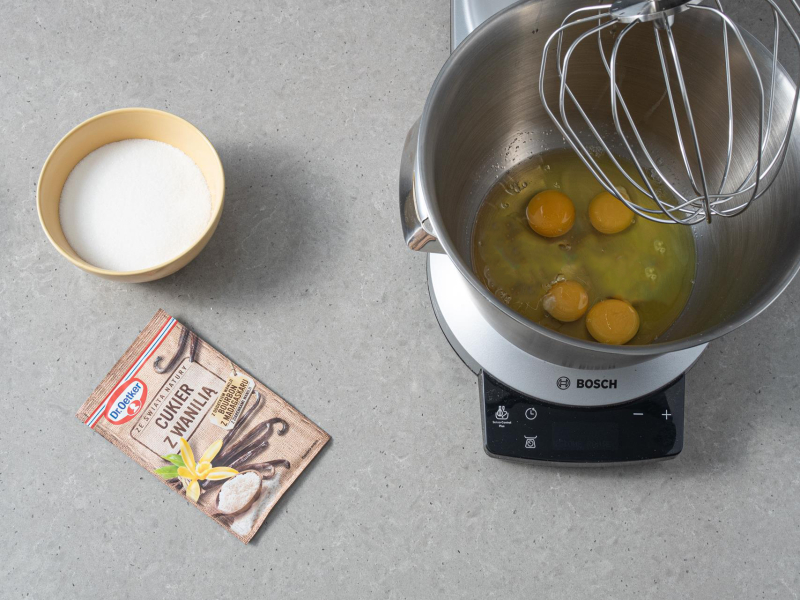 Jajka ubite w misie. Obok cukier z miseczce i cukier z wanilią Dr. Oetkera