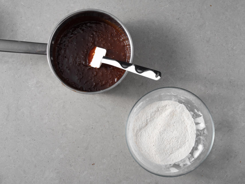 W misce wymieszane suche składniki. Obok w garnku masa czekoladowa.