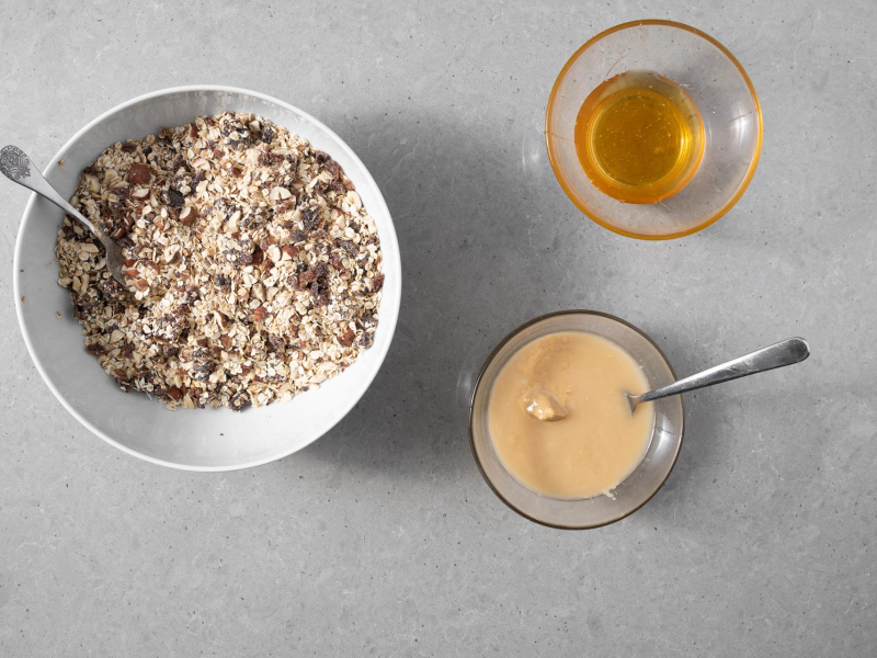 W dużej misie masa na batony fit. Obok w miseczkach masło orzechowe i miód.