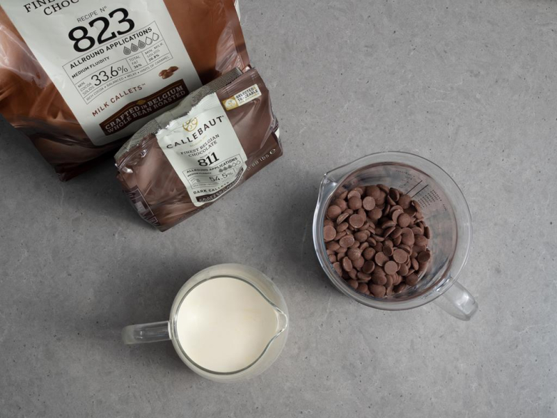 kaletki czekolady callebaut w naczyniu szklanym obok śmietanka