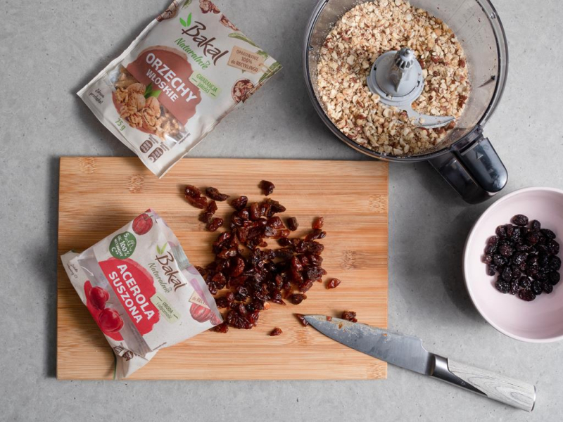 na desce posiekane suszone owoce obok  w malakserze orzechy