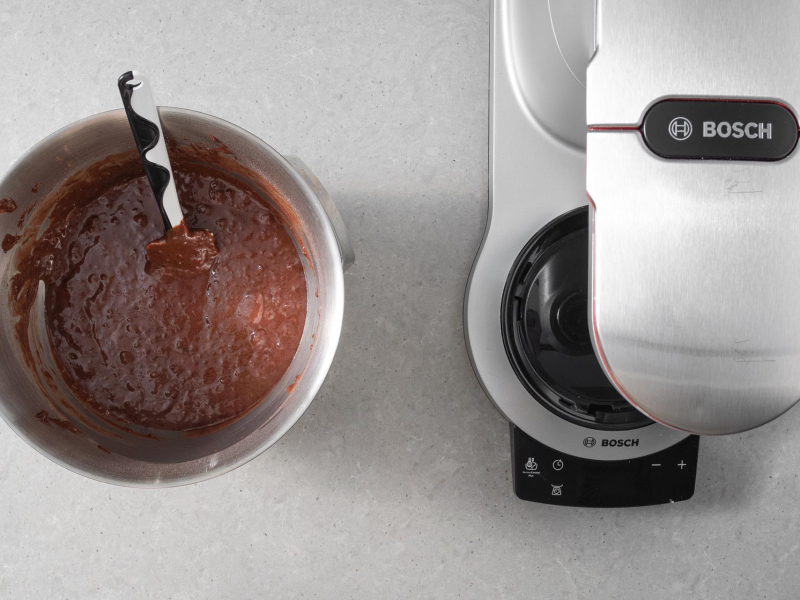 Wymieszane ciasto czekoladowe w misie miksera firmy Bosch. Obok robot kuchenny firmy Bosch.