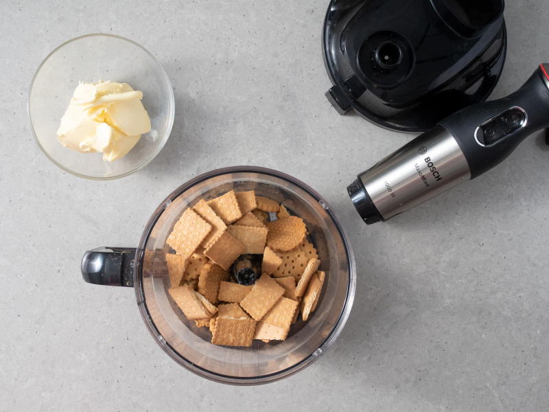 W malakserze firmy Bosch pokruszone herbatniki. Obok w miseczce margaryna.