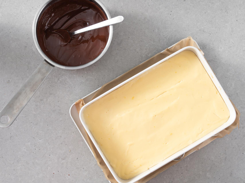 W garnku polewa z czekolady na tofurnik. Obok gotowa masa na gotowany sernik wegański w blaszce.