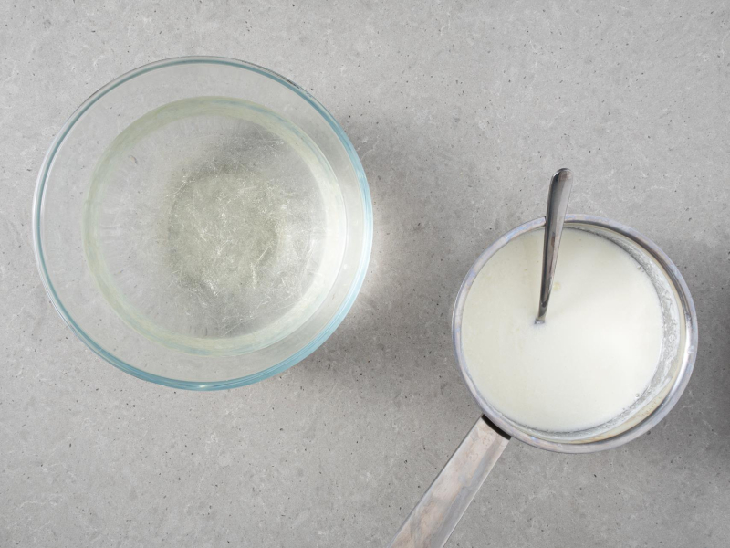 W garnku podgrzany jogurt. Obok listki żelatyny w misce.