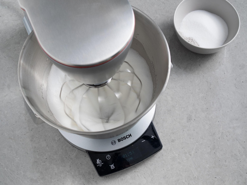 Ubijanie białek robotem kuchennym firmy Bosch. Obok w miseczce cukier.