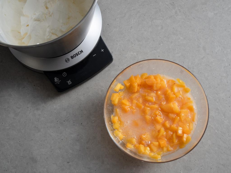 w misie robota ubity krem śmietankowy, w miseczce pokrojone brzoskwinie