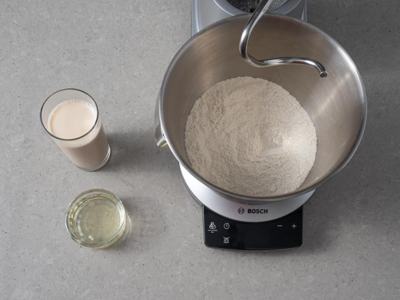 W misie miksera wymieszane suche składniki. Obok napój sojowy i olej rzepakowy.