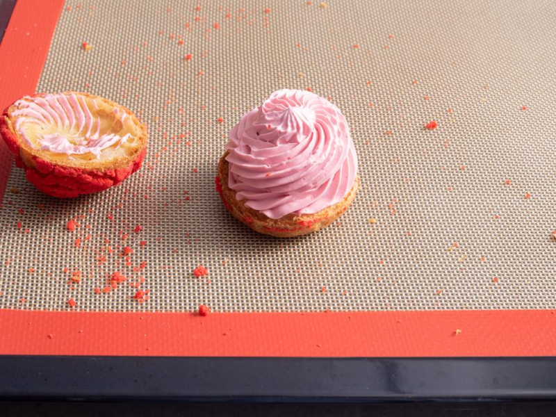 przekrojony ptyś z czerwoną kruszonką nadziany różowym kremem