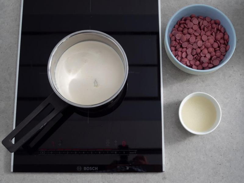 śmietanka w rondelku na płycie indukcyjnej bosch, w miseczce czekolada Ruby Callebaut