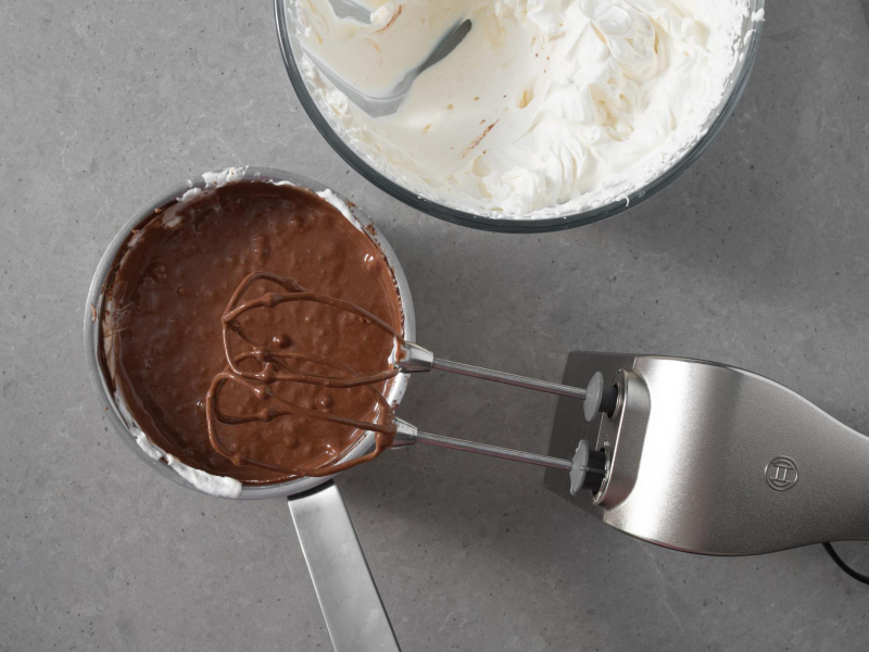 W garnku czekolada wymieszana z mleczkiem kokosowym. Obok ubita śmietanka wegańska.