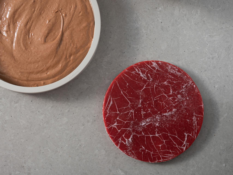 Na blacie mus czekoladowy wyłożony do formy. Obok galaretka truskawkowa.