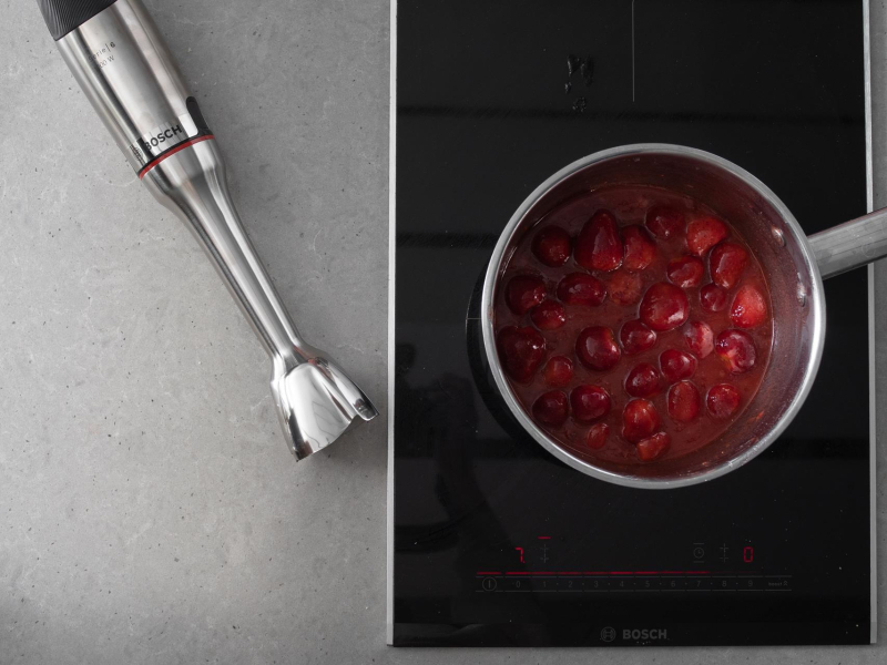 W garnku składniki do żelki truskawkowej. Obok blender ręczny firmy Bosch.