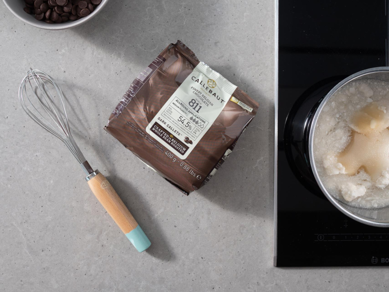 Na blacie czekolada ciemna callebaut 811. Obok w garnku mleczko kokosowe z agarem i z cukrem.