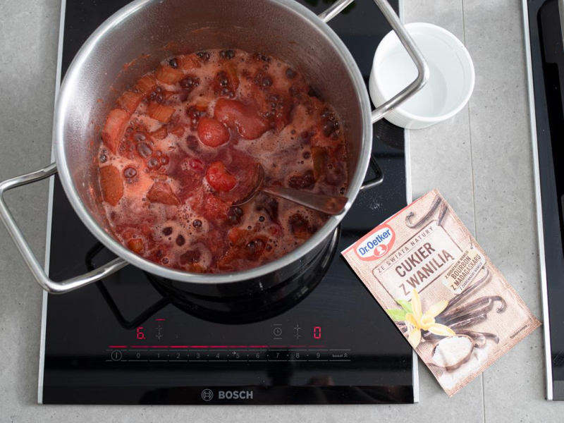 w garnku gotujące się  owoce na sorbet obok cukier z wanilią