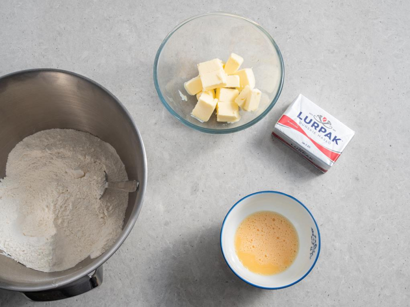 składniki na kruche ciasto: mąka, masło, jajka w miseczkach
