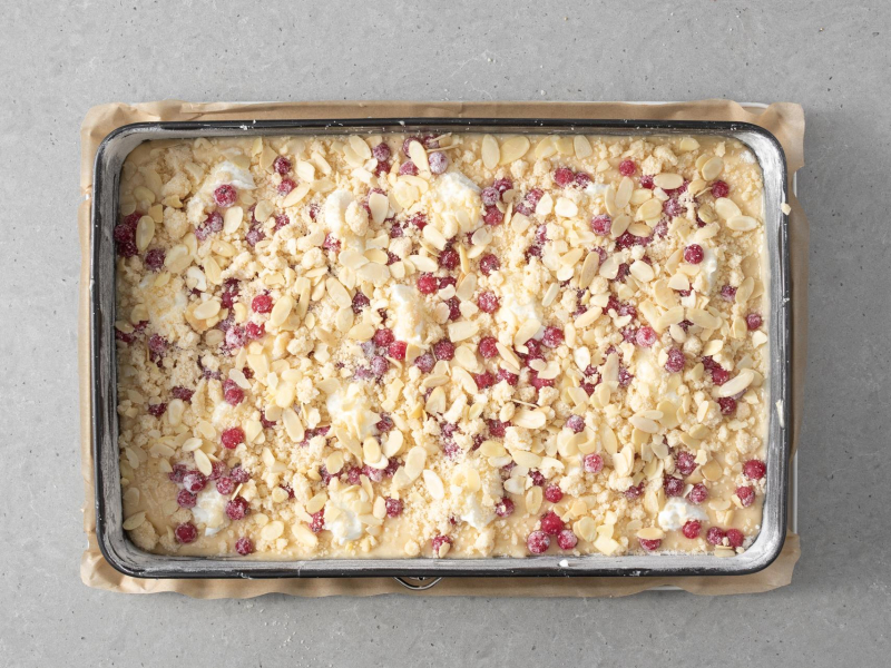 Ciasto na maślance z porzeczkami, serkiem i kruszonką przed upieczeniem.