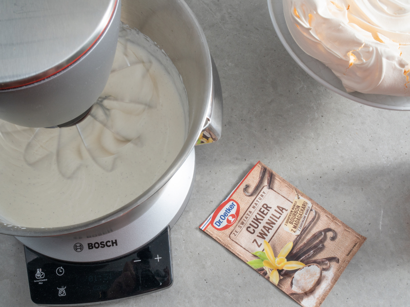 ubijana śmietanka w robocie kuchennym obok cukier z wanilią dr. oetkera