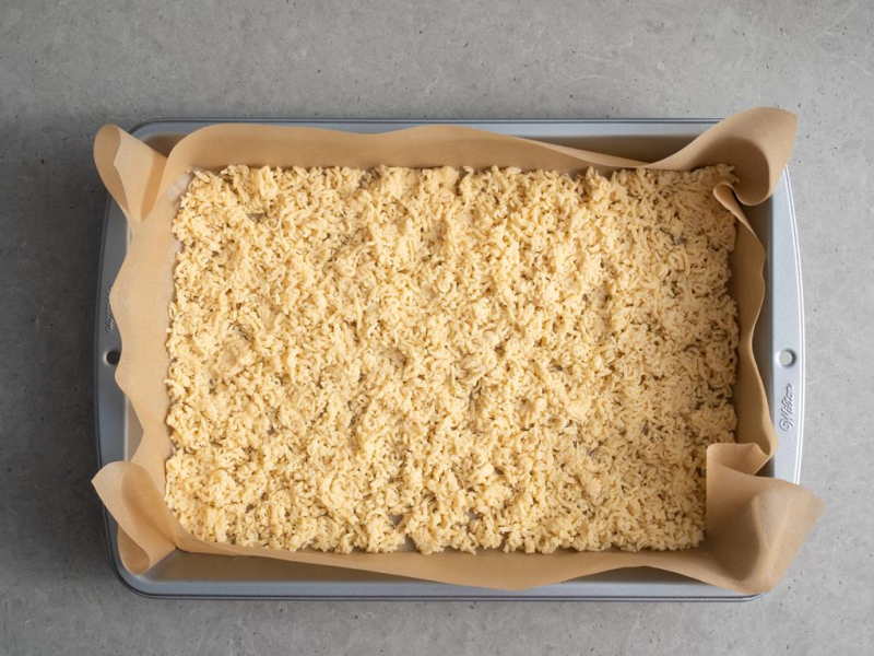 w formie do pieczenia wyłożonej papierem do pieczenia starte ciasto na dużych oczkach