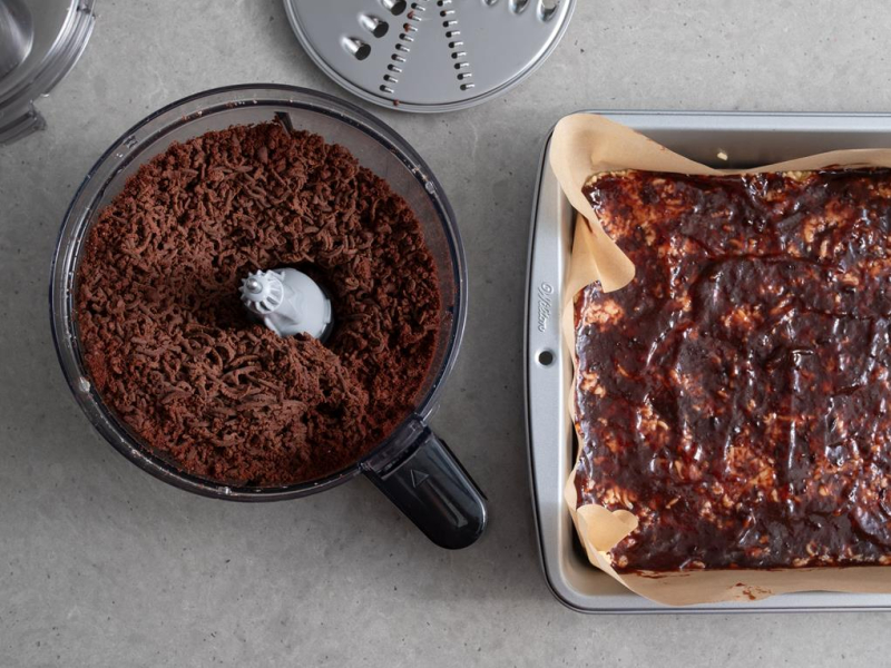 w formie ciasto z dżemem obok w malakserze starte kakaowe ciasto