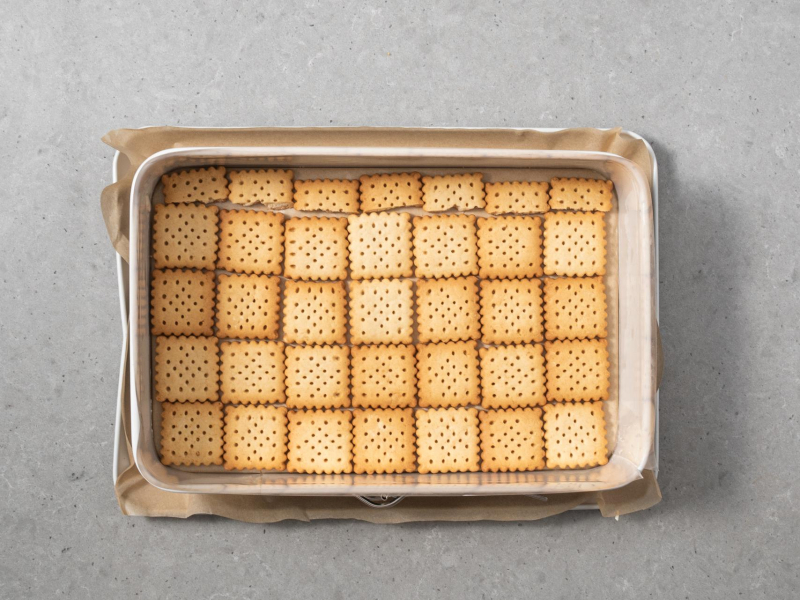 Prostokątna forma wyłożona herbatnikami.