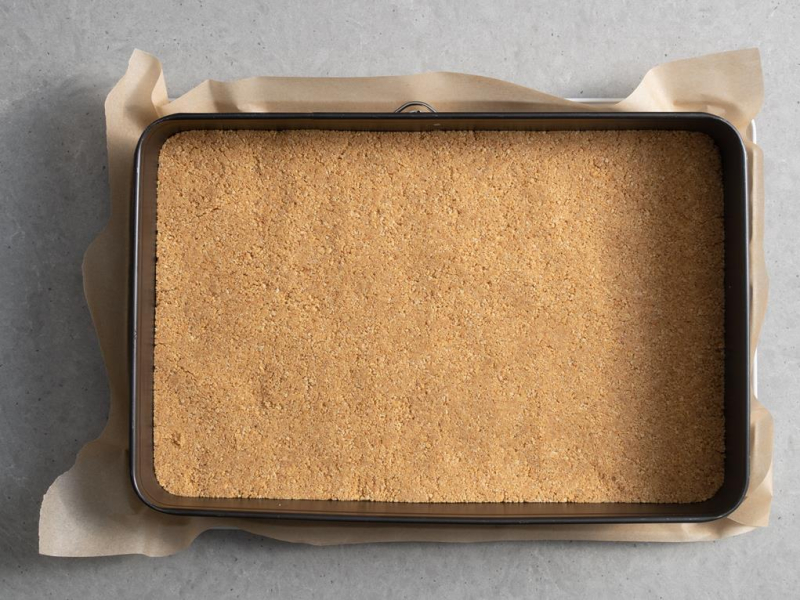 Na dnie formy do pieczenia wyłożony spód z pokruszonych herbatników