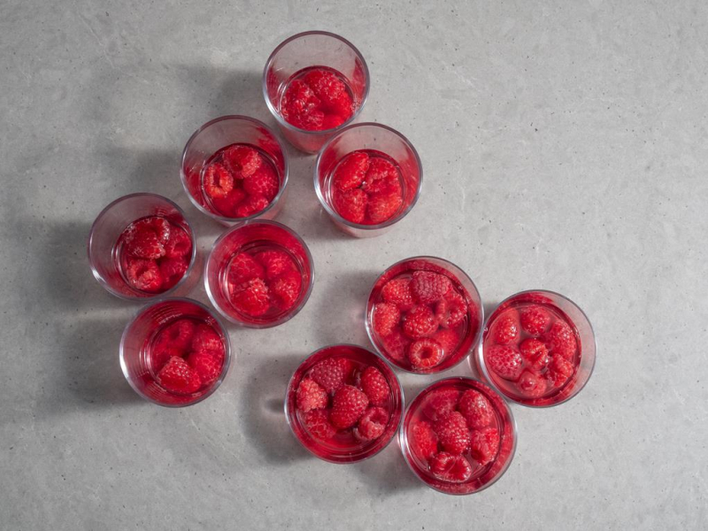 w szklaneczkach poukładane na dnie maliny z galaretką