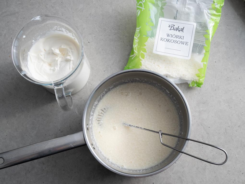 w szklanym naczyniu ubita śmietanka obok rondelak z masa na semifreddo kokosowe