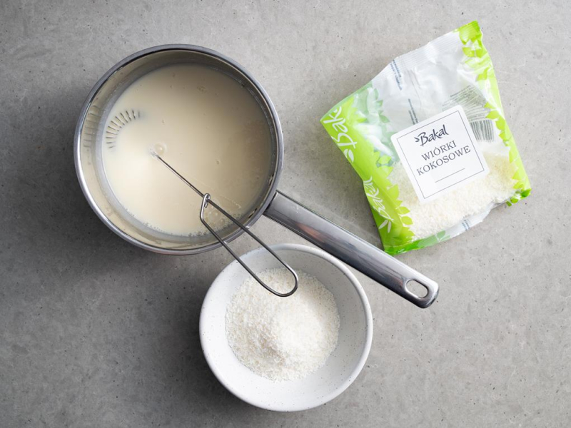 w miseczce wiórki kokosowe oraz rondelek z mlekiem kokosowym i białą czekoladą