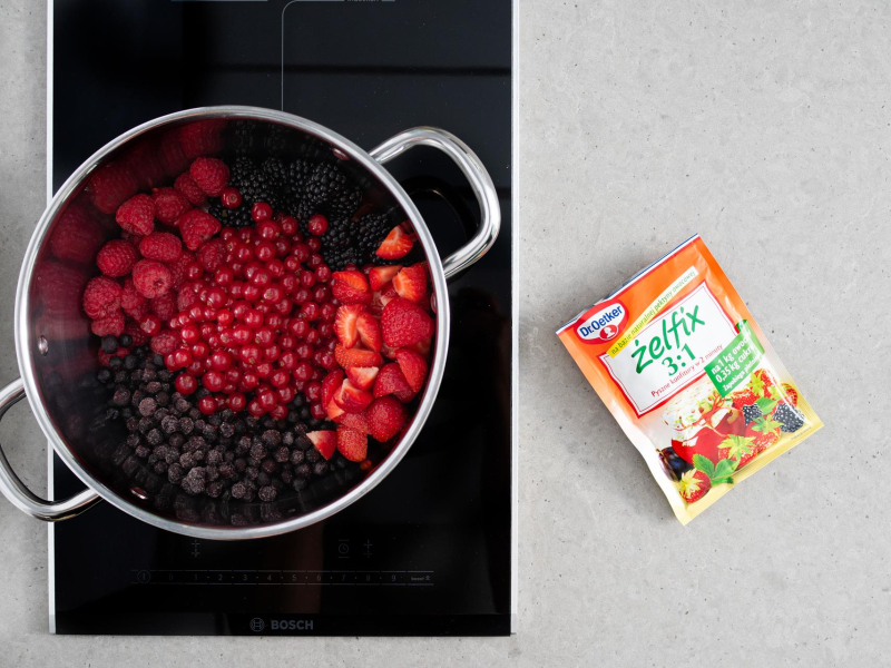 Przygotowane owoce w garnku. Obok na blacie opakowanie żelfix'u 3:1