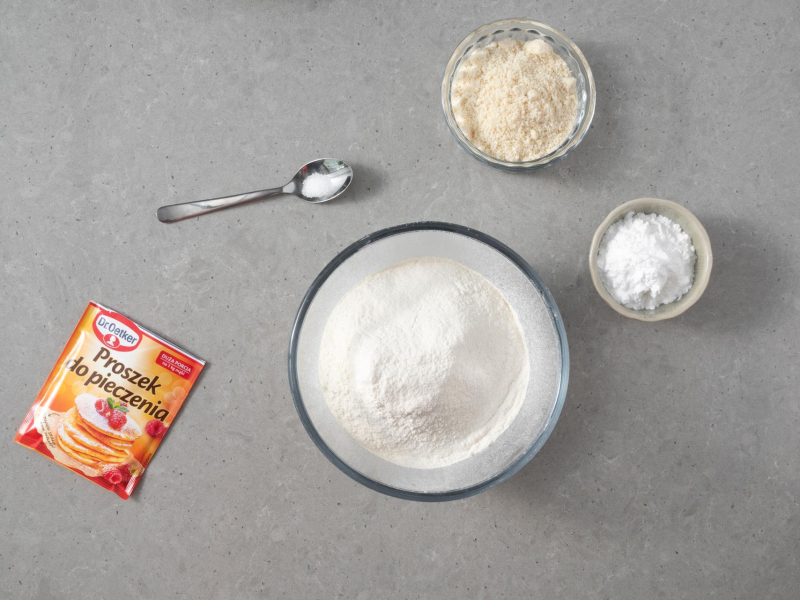Na blacie rozłożone sypkie produkty potrzebne do przygotowania ciasta ze śliwkami bez jajek.