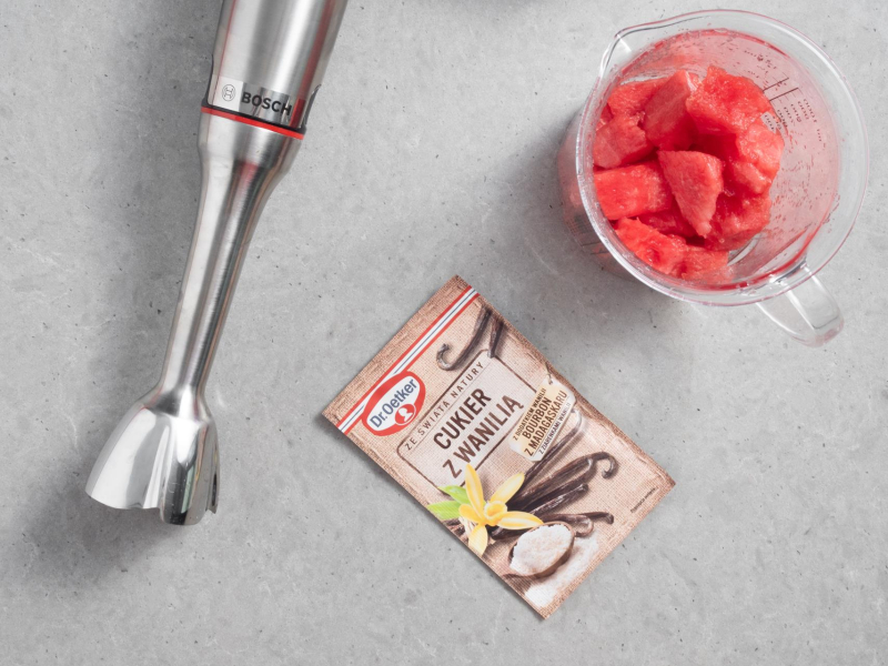 Na blacie kuchennym blender ręczny firmy Bosch, cukier z wanilią Dr. Oetkera oraz arbuz  w wysokim naczyniu.