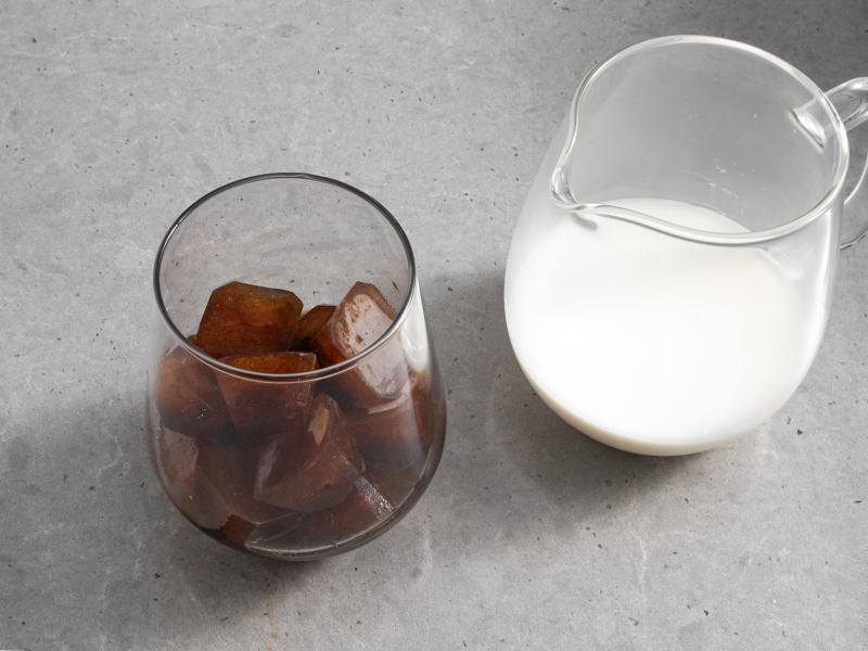 W szklance zamrożone kostki kawy z likierem amaretto i syropem czekoladowym. Obok mleko w  dzbanku.