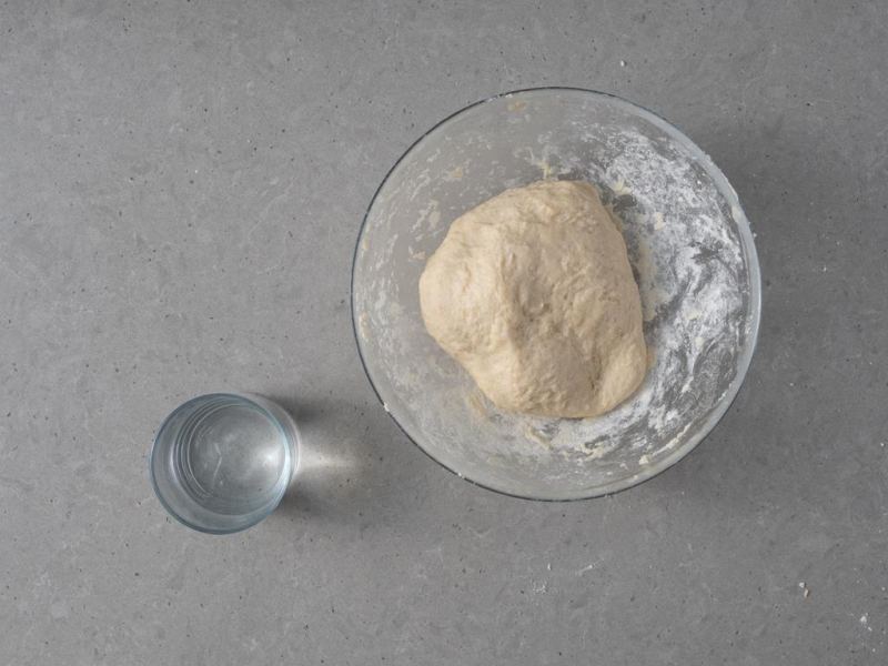 Ciasto na faworki w misce. Obok szklanka z wodą.