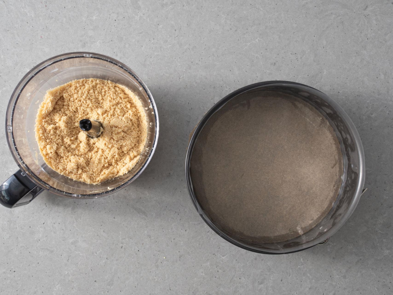 Forma wyłożona papierem do pieczenia. Obok pokruszone herbatniki w malakserze.