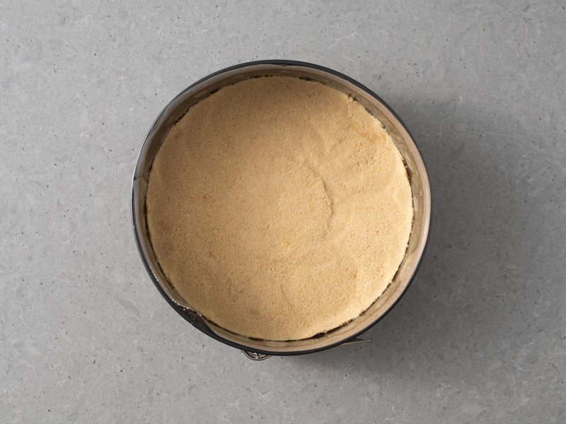Okrągła forma wyłożona spodem z pokruszonych herbatników.