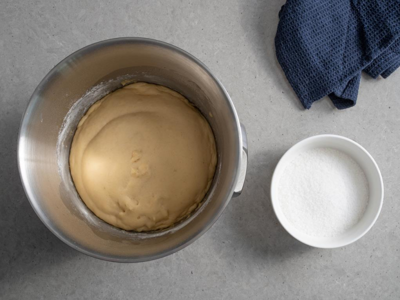 wyrośnięte ciasto drożdżowe obok w miseczce  gruby cukier