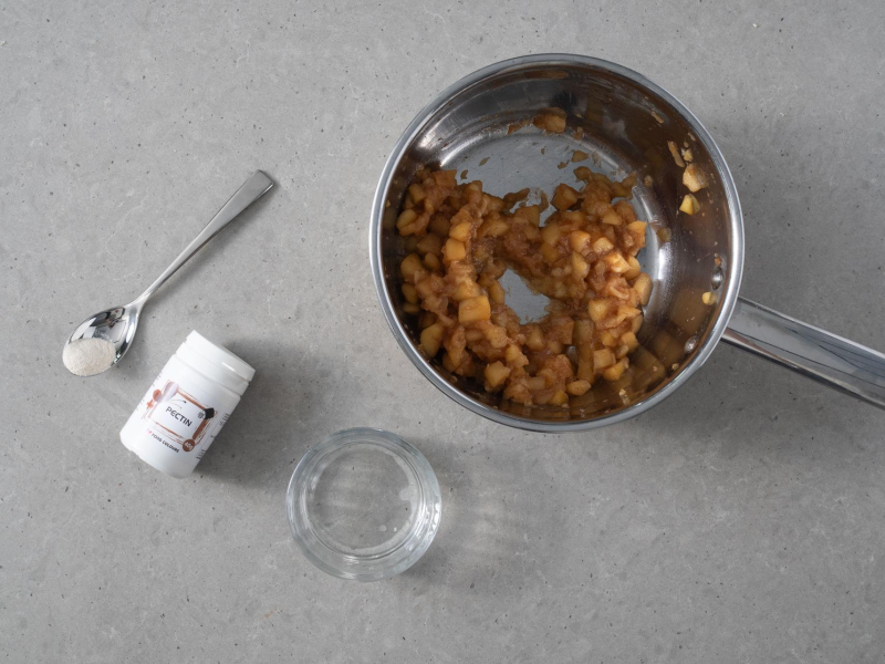 W garnku pokrojone jabłka. Obok opakowanie pektyny Food Colours.