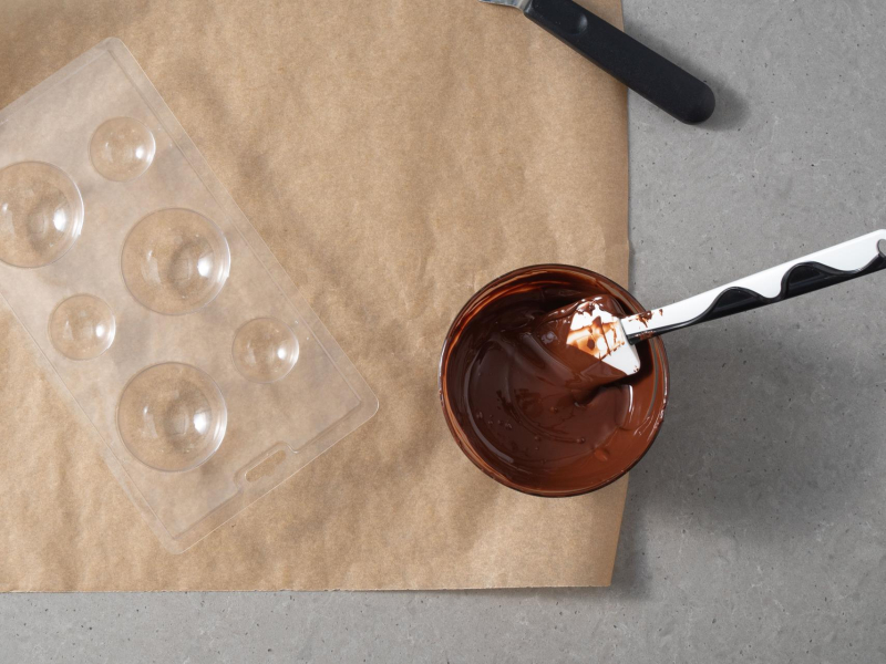 W miseczce rozpuszczona czekolada, a obok forma plastikowa do tworzenia kul czekoladowych.