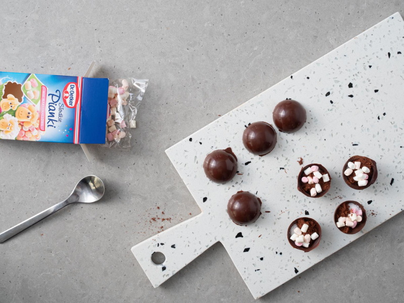 Słodkie mini pianki Dr. Oetkera, a obok na desce czekoladowe kule do mleka.
