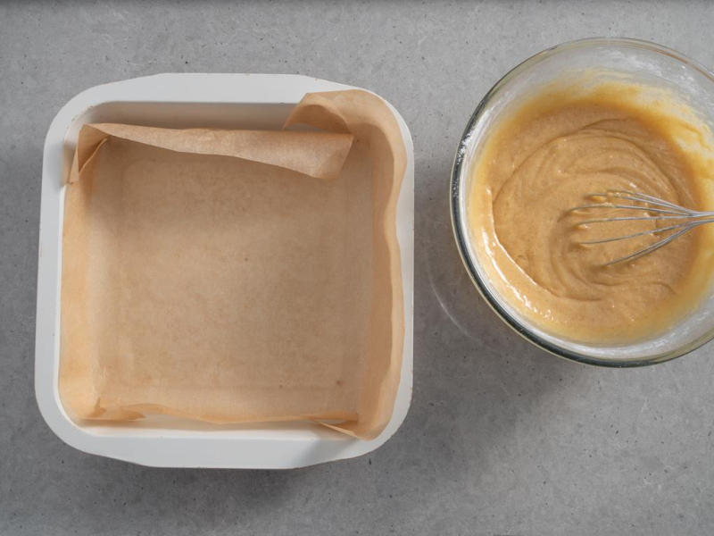 kwadratowa foremka wyłożona papierem do pieczenia, w misce masa na karmelowe blondie